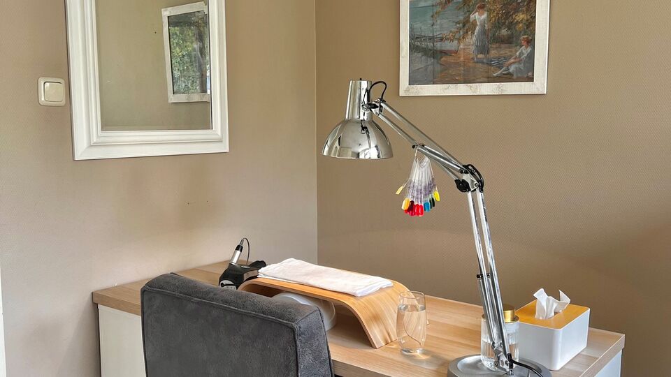 De werkplek van Salon Bloom: een houten tafel met een zilveren bureaulamp en ingelijste prenten aan de muur